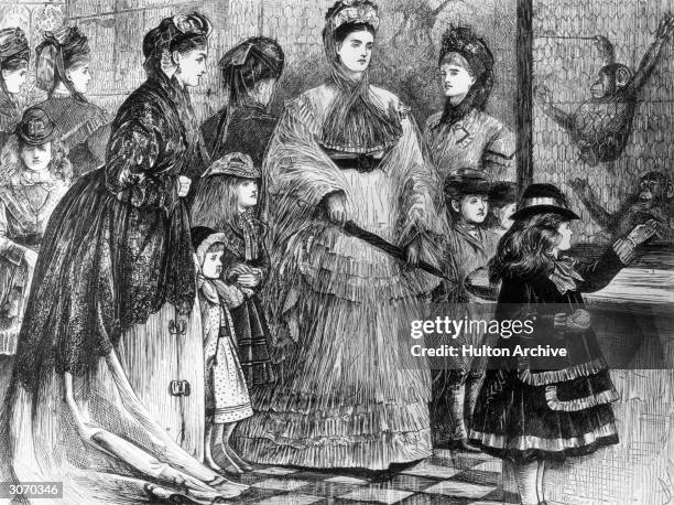 Group of well-to-do Victorian ladies and their children visit the monkey house in the zoological gardens, Regents Park, London, at a time when great...