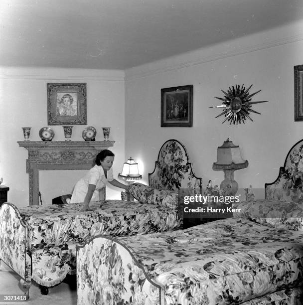 Maid smooths out the counterpane in the bedroom in which screen icon Marilyn Monroe will sleep during her stay in England. The star has taken a...