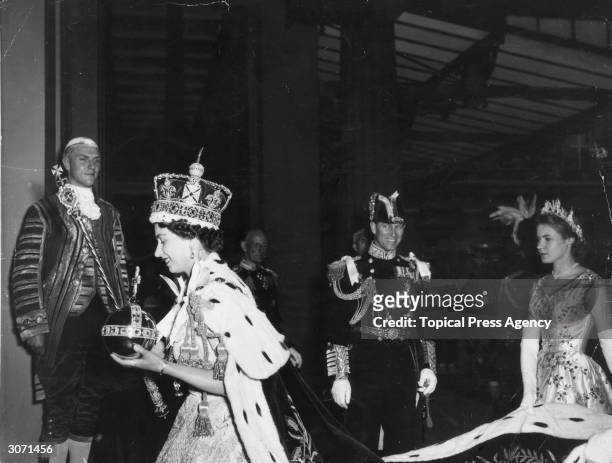 Queen Elizabeth II, wearing the Imperial State crown and carrying the Orb and Sceptre, returns to Buckingham Palace from Westminster Abbey, London,...