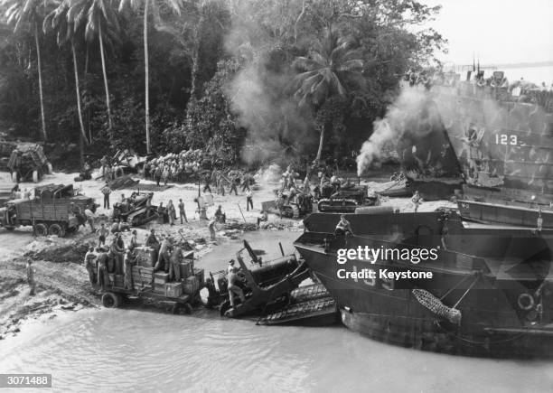 American and New Zealand troops use caterpillar tractors to unload landing craft at a beach on the Green Islands, 130 miles of Rabaul, New Britain.