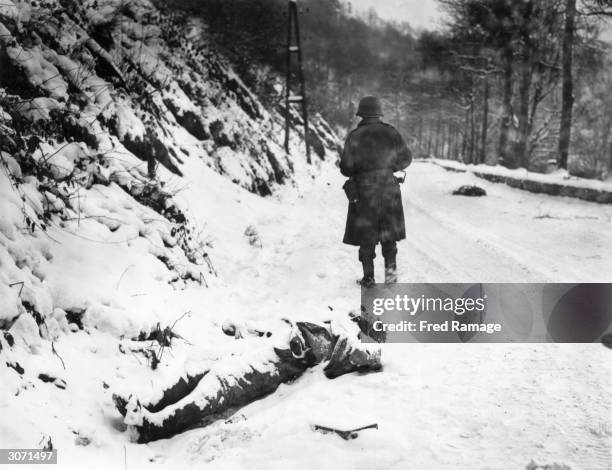 Dead German soldier covered in snow on the road to the town of La Roche in the northern half of the Ardennes, which was captured by British and...