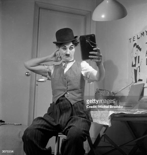 Austrian actress and impersonator Telmy Talia checks her make-up after her uncanny transformation into Charlie Chaplin for a Paris nightclub show.