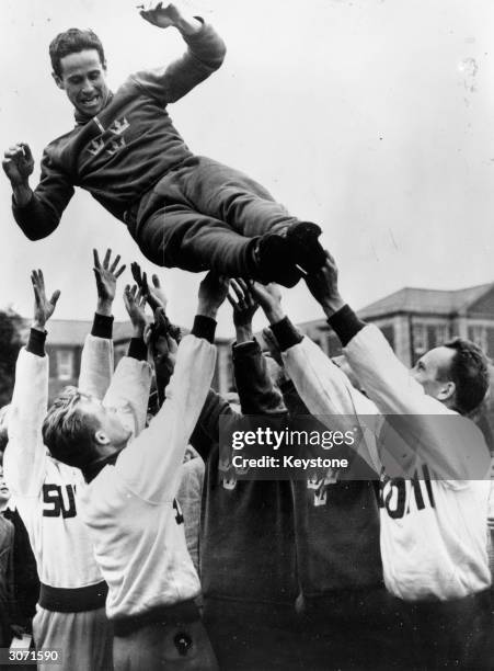 Members of the team toss the winner of the pentathlon, Captain Willian Grut of Sweden into the air. By winning three of the events outright he...