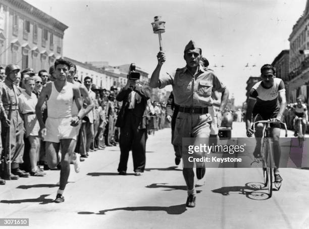 The Olympic flame carried by an Italian cadet through the streets of Bari on its way to London for the opening ceremony.