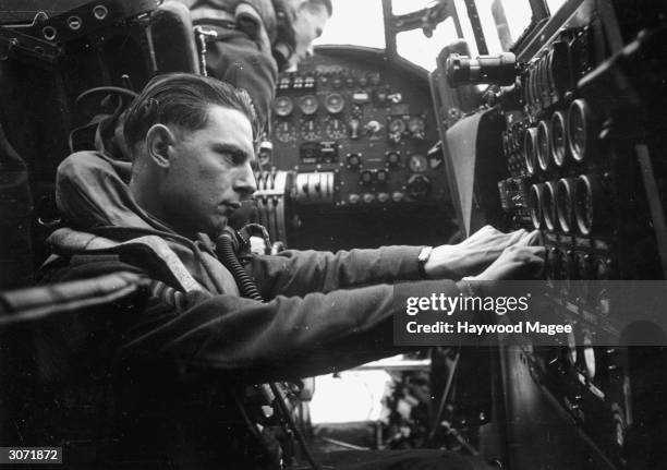 Flight engineer checks the emergency petrol pump and engine instruments on board a Lancaster bomber. Original Publication: Picture Post - 1437 - The...