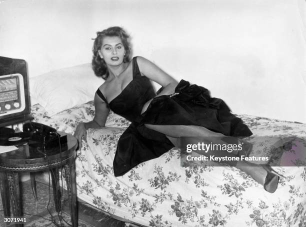 Film star Sophia Loren relaxes on a couch in her Rome apartment before an evening out.