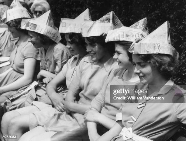 Schoolgirls from Gravesend Grammar School wear newspaper hats to protect them from the sun while they are watching Wimbledon during a heatwave.