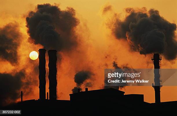 smokestacks at chemical plant silhouetted with setting sun behind - port talbot bildbanksfoton och bilder