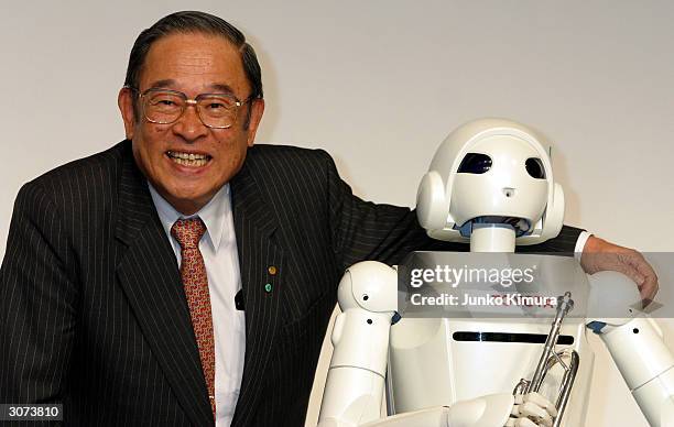 Fujio Cho, the President of Toyota Motor Corporation poses next to the companies newly developed prototype of a walking robot during a press...