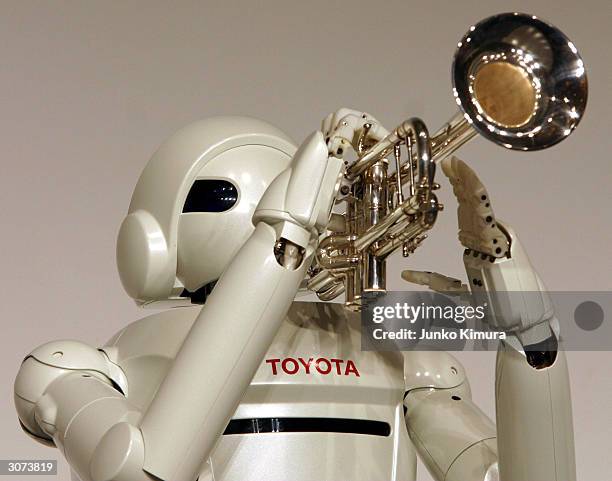 Toyota Motor Corporation's newly developed prototype of a walking robot, blows and plays a trumpet during a press conference on March 11, 2004 in...