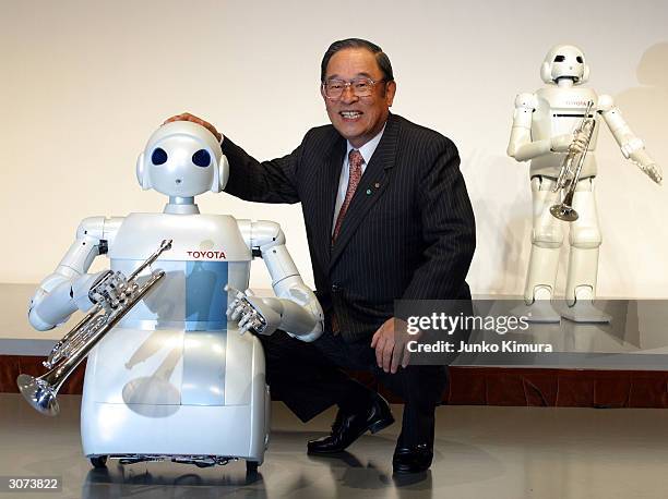 Fujio Cho, the President of Toyota Motor Corporation poses next to the companies newly developed prototype of a rolling robot during a press...