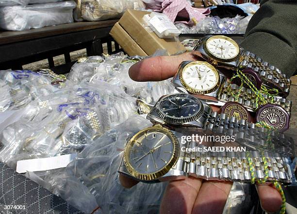 An unidentified Thai customs officer shows counterfeit Rolex watches confiscated in different raids during a display at the customs house in Bangkok,...