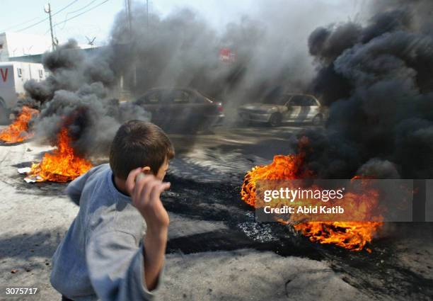 Palestinian throws a stone at riot police near burning tyres outside the court hearing the trial of four Palestinian taxi drivers accused of raping...