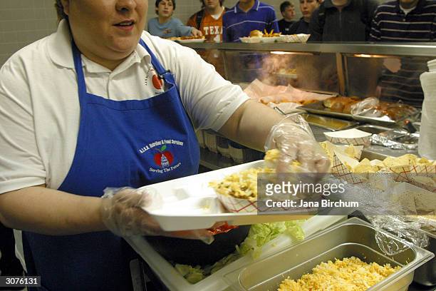 An employee of the cafeteria at Bowie High School serves up food during lunch March 11, 2004 in Austin, Texas. The Austin School District is working...