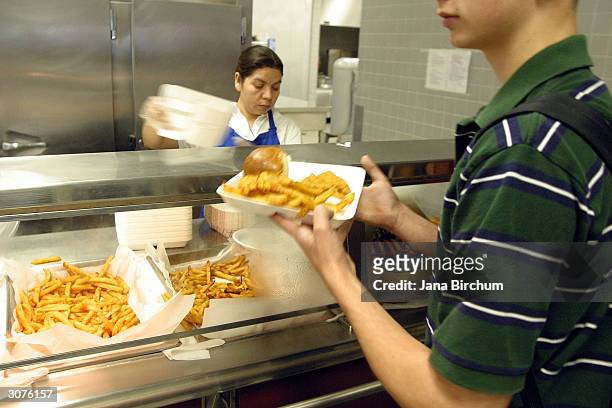 An employee of the cafeteria at Bowie High School serves food to a student during lunch March 11, 2004 in Austin, Texas. The Austin School District...