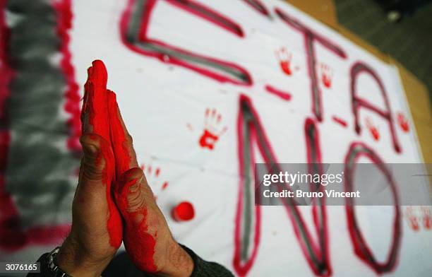 Man creates an anti-Eta banner with palm prints of red paint near the scene of the commuter train March 11, 2004 after it was devastated by a bomb...