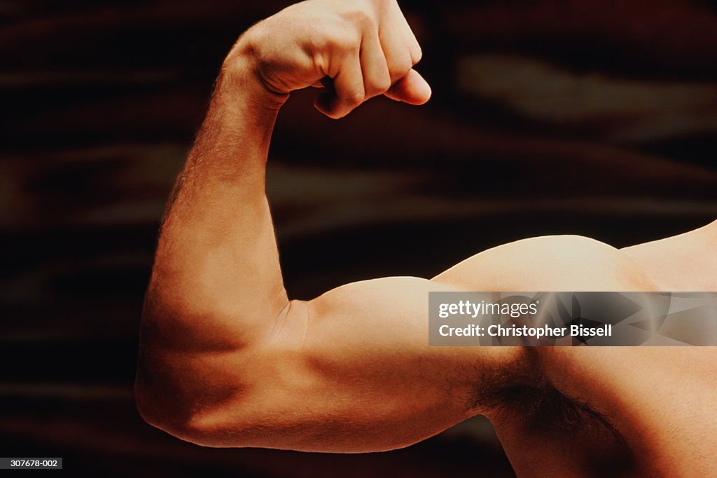 Man flexing bicep muscle, close-up