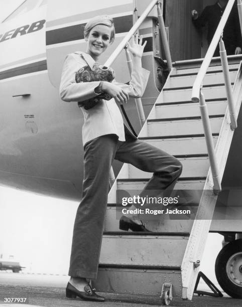 British fashion model Twiggy boards an aircraft at Heathrow, bound for Tunisia on an export drive for Berkertex, 28th September 1966.