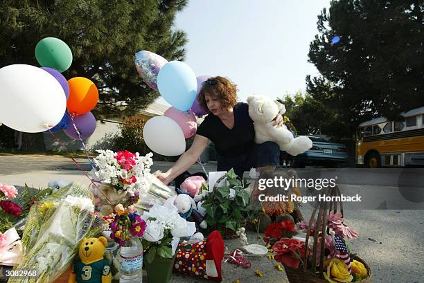 Neighborhood resident Yvonne Medina places items at the memorial in front of the house March 13, 2004 in Fresno, California. According to reports,...