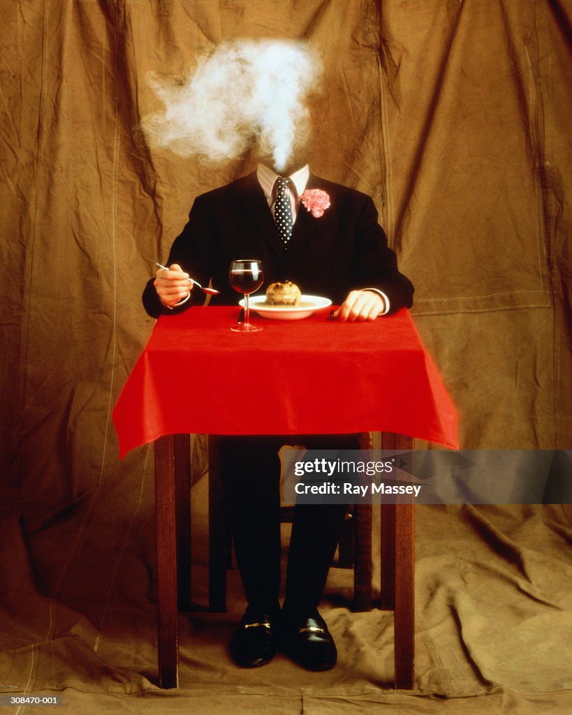 Headless man in suit at table, about to eat soup with toad in