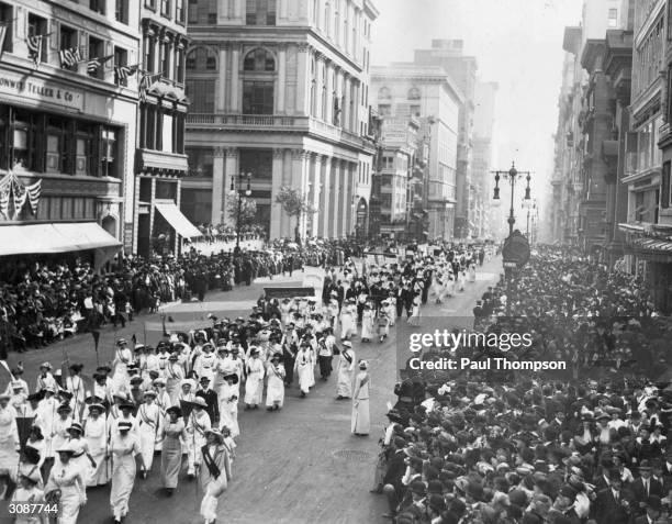 Crowds line the sidewalks to watch a Women's Suffrage Movement march through New York City.