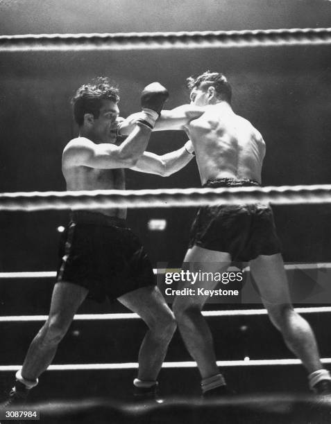 In a boxing match at Harringay, London, Bruce Woodcock misses with a left handed punch to Freddie Mills's face. He went on to outpoint Mills in a...