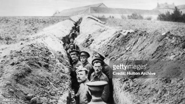 British soldiers lined up in a narrow trench during World War I.