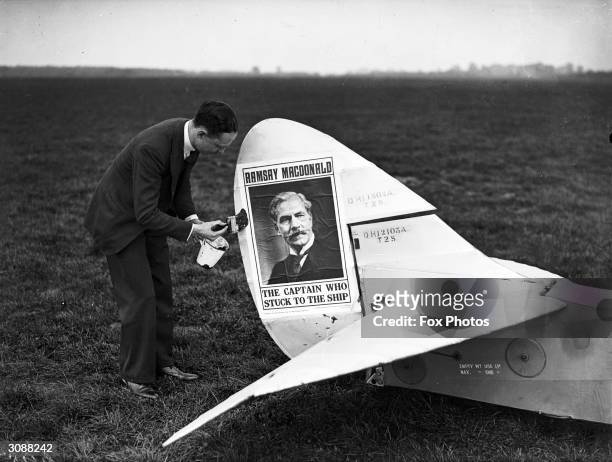 Mr Mahony pastes an election poster for Labour politician Ramsay MacDonald on the tail of his aeroplane at Heston airfield.
