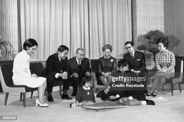 In the Imperial Palace, Tokyo watching the children play pinball are: left to right, Crown Princess Michiko and Crown Prince Akihito, Emperor...