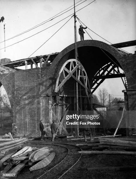 Workmen remove the scaffolding from one of the completed arches of the viaduct beyond Chase Side in Southgate, part of the extension of the...