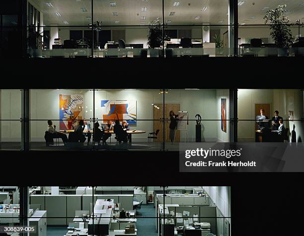 executives in meeting, view through windows of office block at night - distant meeting stock pictures, royalty-free photos & images