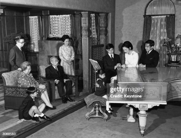 New Year photograph showing the Japanese Imperial Family at the Imperial Palace, Tokyo. They are watching the youngest member of the family play the...