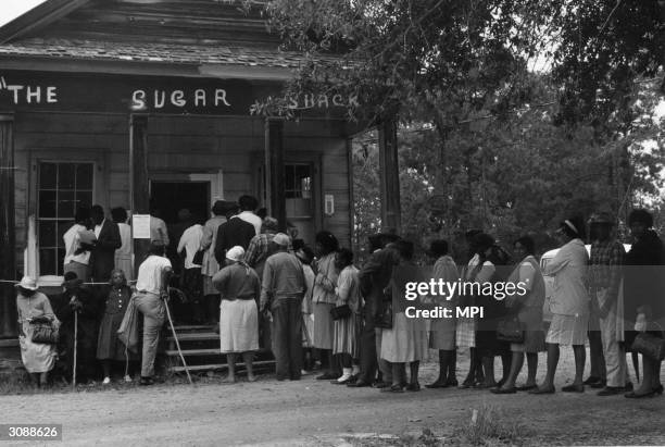 Group of voters lining up outside the polling station, a Sugar Shack small store, in Peachtree, Alabama, after the Voting Rights Act was passed the...