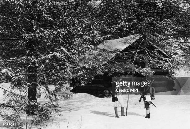 Two men dressed as colonial soldiers standing outside one of the reconstructed log cabins in Valley Forge National Historical Park, Pennsylvania. The...