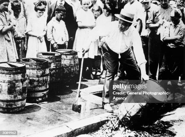 Man destroying barrels of alcohol during prohibition in America.