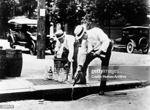 Two men pouring alcohol down a drain during prohibition in America.