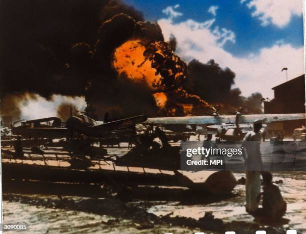 Black clouds of smoke pour from aircraft ablaze on a military airfield near Pearl Harbour , Oahu Island after a surprise attack by the Japanese which...