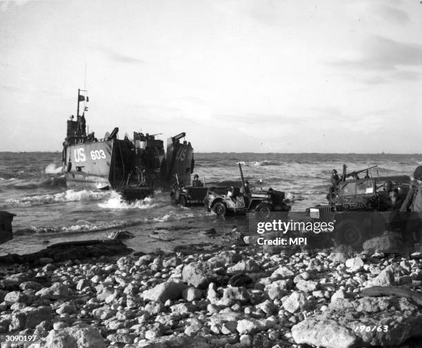 Jeeps of the 5th Engineer Special Brigade debark from a Landing Ship Tank at Fox Green, Omaha Beach, Normandy, to aid the Army of Liberation on the...