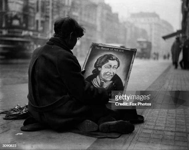 Pavement artist in the Strand near Charing Cross Station, London completes a portrait of the 'Queen of the Air', aviatrix Amy Mollison.