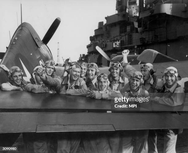 American pilots leaning against the tail of a F6F Hellcat on board the USS Lexington after a raid on the Marshall Islands.