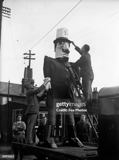 Locals put the finishing touches to a giant guy which is mounted on a lorry for a procession through the streets of Staines in Surrey on Bonfire...