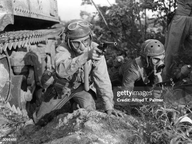 Wearing a gas mask and firing hand guns, M-3 tank crews training at Fort Knox to meet any situation.