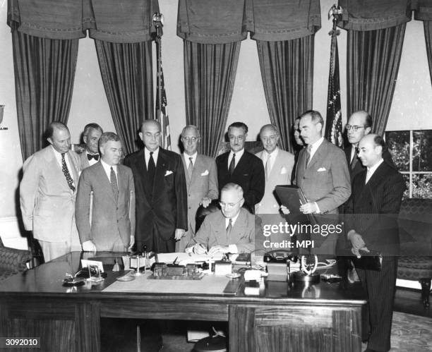 President Harry S. Truman signing the North Atlantic Treaty which marked the beginning of NATO, behind him are Sir Derrick Hoyes Miller, Henrik de...