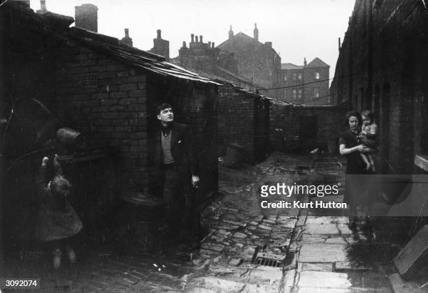 Year-old unemployed miner outside his home in the Hardybutts, a row of slum houses in Wigan, Lancashire, November 1939. The miner has been out of...