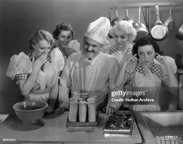 An MGM 'chef' shows off his cooking to a group of giggling girls. A scene in 'Vital Victuals', an MGM short.