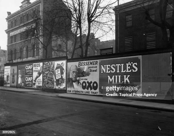Wall of posters in Camberwell, London advertising various products such as Nestle's Milk, Oxo, Camp Coffee and Marmite.