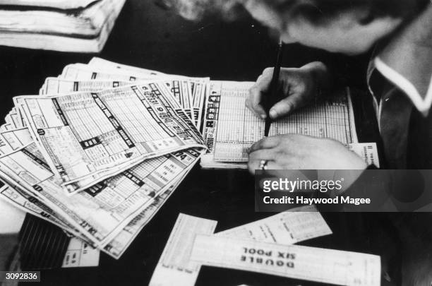 Clerk checks one of the thousands of football coupons which flood into Littlewoods every week with one adult in three playing the pools. Original...