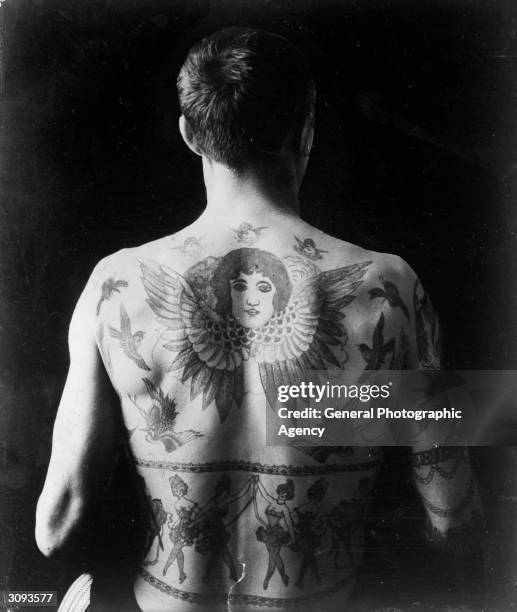 Man's back tattooed with cherubs and dancing girls.