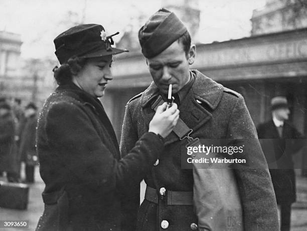 An AFS girl lights a cigarette for a 'doughboy' or US soldier upon his arrival in London from Northern Ireland.