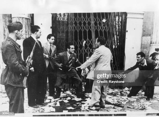 Italian anti-Fascists point their guns at a suspected pro-Fascist. He has been pulled from a shop that the anti-Fascists have just bombed.